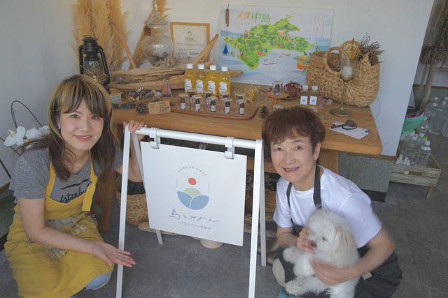 看板の前で笑顔を見せる母と娘と看板犬