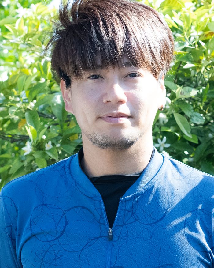 柑橘畑の前に立つ久保さん
