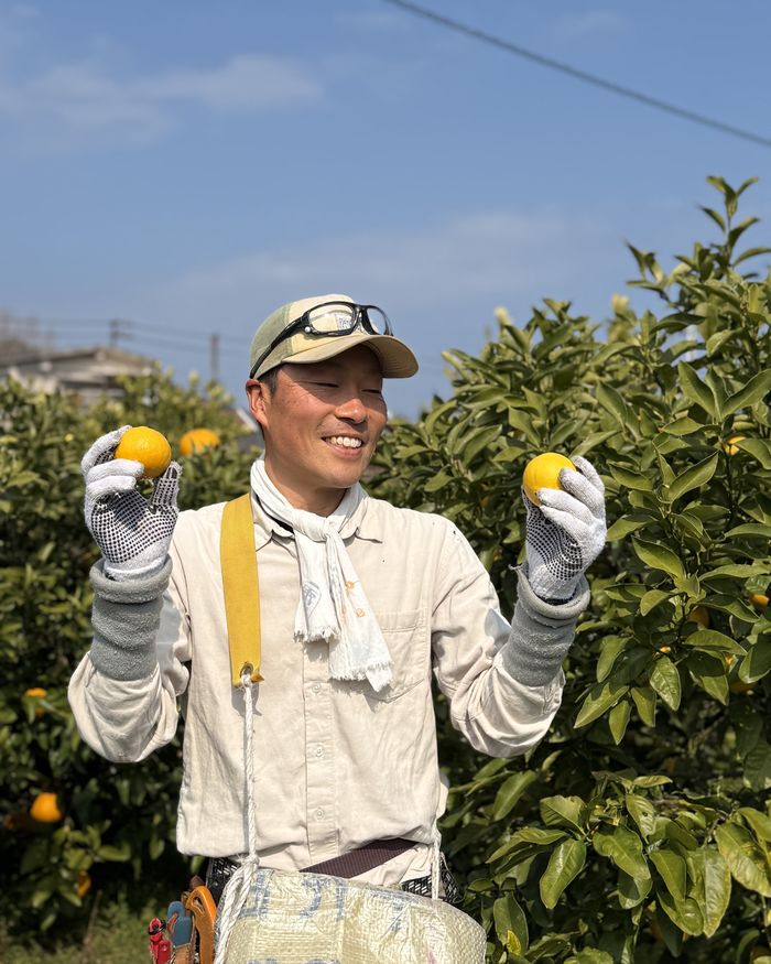 柑橘を手に笑う清水さん