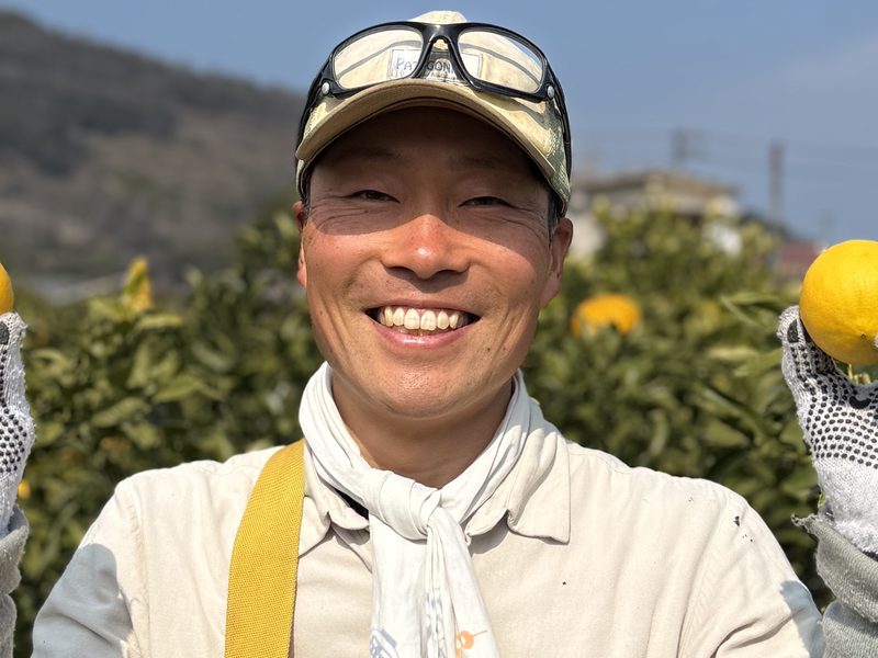 柑橘を手に笑顔を見せる清水雄矢さん