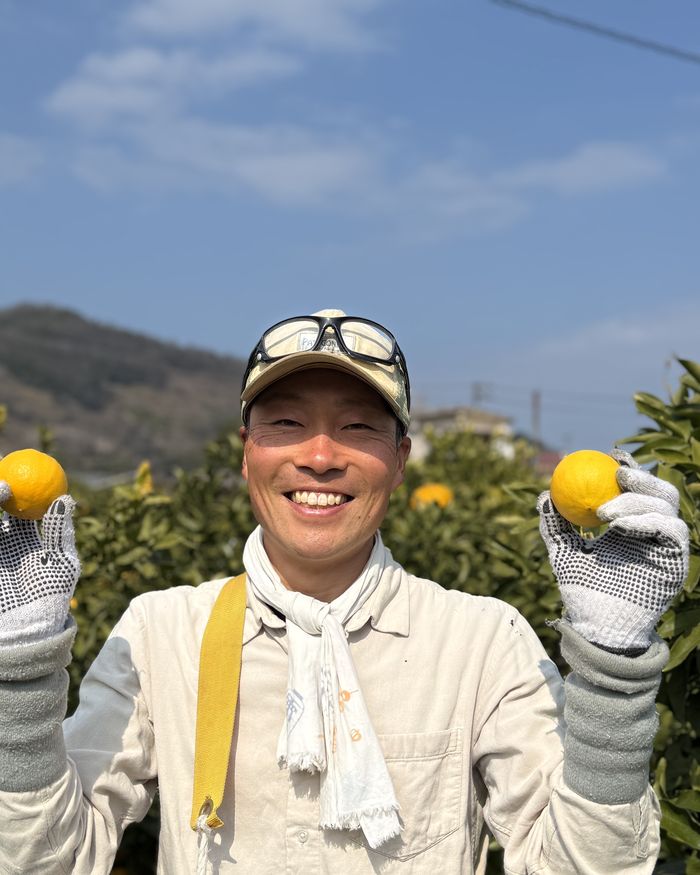 柑橘を両手に笑顔を見せる清水雄矢さん